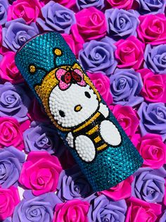 a hello kitty phone case sitting on top of purple roses