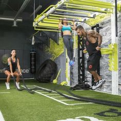 two people doing crossfit exercises in a gym with green walls and artificial turf