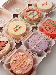 an assortment of cupcakes in trays with frosting designs on the top