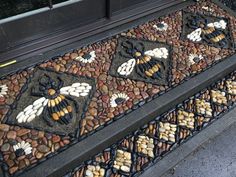 a mosaic design on the side of a building with rocks and stones around it, in front of a window