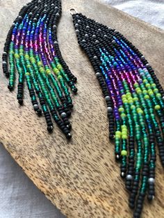 a pair of beaded earrings sitting on top of a wooden board