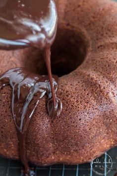 chocolate frosted bundt cake on cooling rack being drizzled with icing