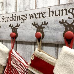 three stockings hanging from hooks on a wooden wall with the words, the stockings were hung