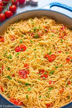 pasta with tomatoes and parsley in a blue skillet next to fresh cherry tomatoes