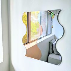 a mirror that is on the side of a wall next to a chair and window