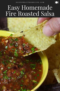 a hand holding a tortilla chip and dipping it into a bowl of salsa