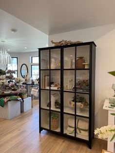 a glass cabinet filled with lots of items on top of a hard wood floored floor