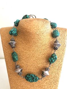 a necklace with turquoise and silver beads on a mannequin