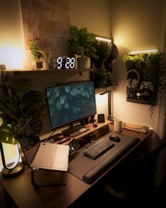 a desk with a computer, keyboard and plant on it in front of a clock