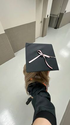 a person wearing a graduation cap with a pink ribbon on it