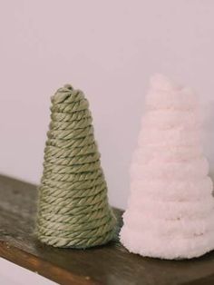 two small white and green cones sitting on top of a wooden shelf next to each other