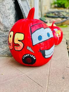 two pumpkins with cars painted on them are sitting on the ground next to each other