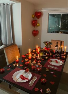 a dining room table set for valentine's day with candles and hearts on it