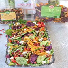 a salad with carrots, spinach and other vegetables in plastic containers on a table