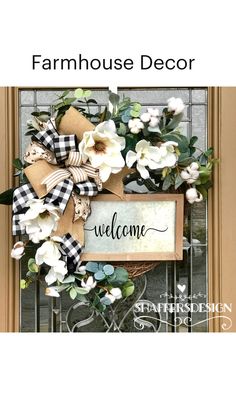 a welcome sign is hanging on the front door with flowers and greenery around it