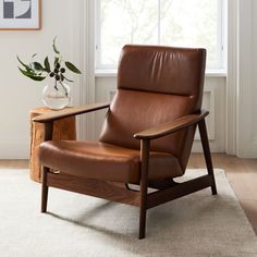 a brown leather chair sitting on top of a white rug next to a wooden table