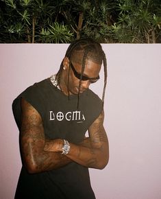 a man with dreadlocks standing in front of a wall looking at his cell phone