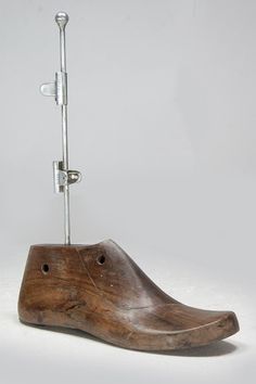 a wooden shoe that is on top of a metal pole with a hook in it