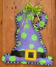 a purple and green witch hat with polka dots on it sitting on top of a wooden floor