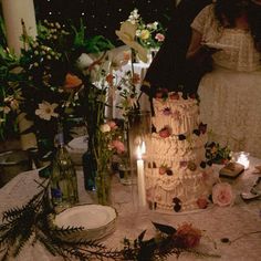 a wedding cake sitting on top of a table next to candles and flowers in vases