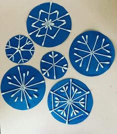 four snowflakes are shown on a white surface and one is made out of blue paper