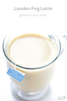 a glass cup filled with liquid on top of a white table next to a tag that says london fog latte