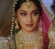 a woman in a bridal outfit with jewelry on her head and veil over her face