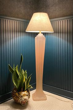 a lamp that is next to a potted plant on a table in a room