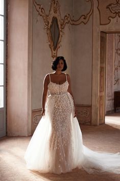 a woman in a wedding dress is walking through the room with her hand on her hip