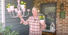 a woman is holding up some flowers and a chandelier in front of her house