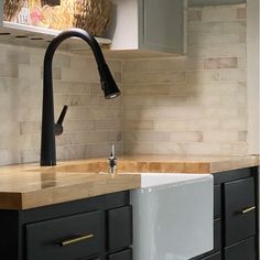 a kitchen sink sitting under a faucet next to a counter top with baskets on it