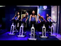 a group of women riding stationary bikes in a room with blue lighting on the walls