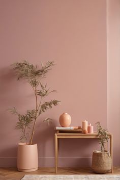 a pink room with two planters and a small table on the floor next to it