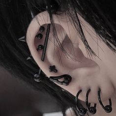 an ear piercing with black spikes and nails on the top of it's ear