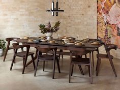 a dining room table with chairs and plates on it in front of a brick wall