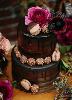 a chocolate cake with flowers and macaroons on top