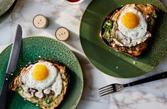 two green plates with eggs on them next to silverware and utensils sitting on a marble table