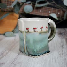 a ceramic mug with mushrooms on it sitting on a table