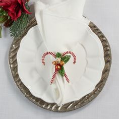 a white plate topped with candy canes on top of a silver platter next to a red flower