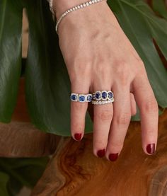 a woman's hand with three blue and white stones on her finger, next to a plant