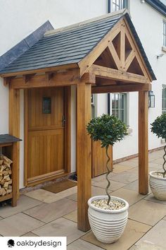 two potted trees in front of a wooden building with a door and window on the side