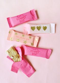 three candy bars with pink wrappers and gold stars on them, one is for power bar