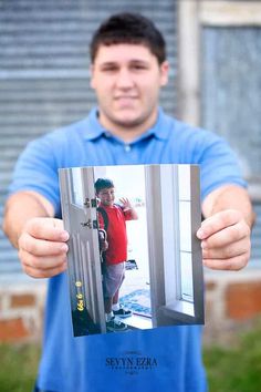 a man in a blue shirt is holding up a photo with the door open and his hand out