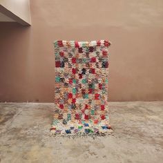 a multicolored rug sitting on top of a cement floor next to a wall