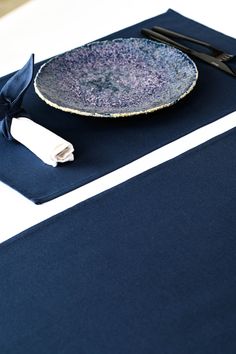 a blue place mat with a black plate on it and some scissors next to it