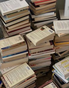 a pile of books sitting next to each other on top of a floor covered in papers