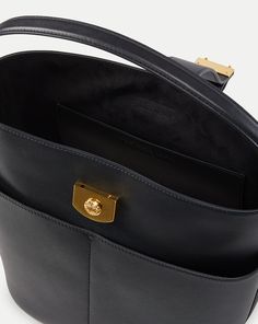 Defined by its sculptural shape, the Crest Lock Bucket bag is an everyday hero. Its distinct yet understated design gives it maximum versatility while it’s relaxed yet sleek look feels of-the-moment. It’s crafted from supple leather and finished with minimalist hardware, including a crest-engraved lock closure. Its luxurious suede interior is finished with a generous flat pocket, while it’s four-compartment exterior allows for further organization. Can be carried as a top handle, crossbody or sh Modern Top Handle Bucket Bag For Business, Modern Bucket Bag With Detachable Handle For Business, Modern Business Bucket Bag With Detachable Handle, Modern Double Handle Bucket Bag For Business, Modern Top Handle Bucket Bag For Office, Modern Business Bucket Bag With Removable Pouch, Modern Rectangular Bucket Bag With Magnetic Closure, Modern Bucket Bag For Office With Top Carry Handle, Modern Office Bucket Bag With Top Carry Handle