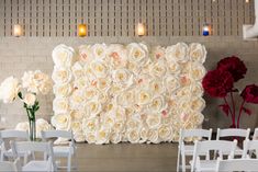 white chairs are set up in front of a large flower wall