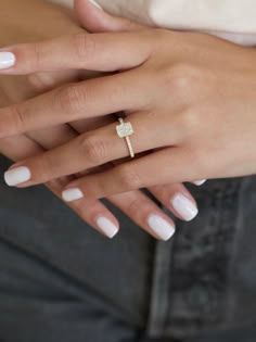 a woman's hand with white manicured nails and a ring on her finger