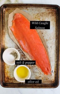 raw salmon on a baking sheet with salt and pepper, olive oil, and seasoning